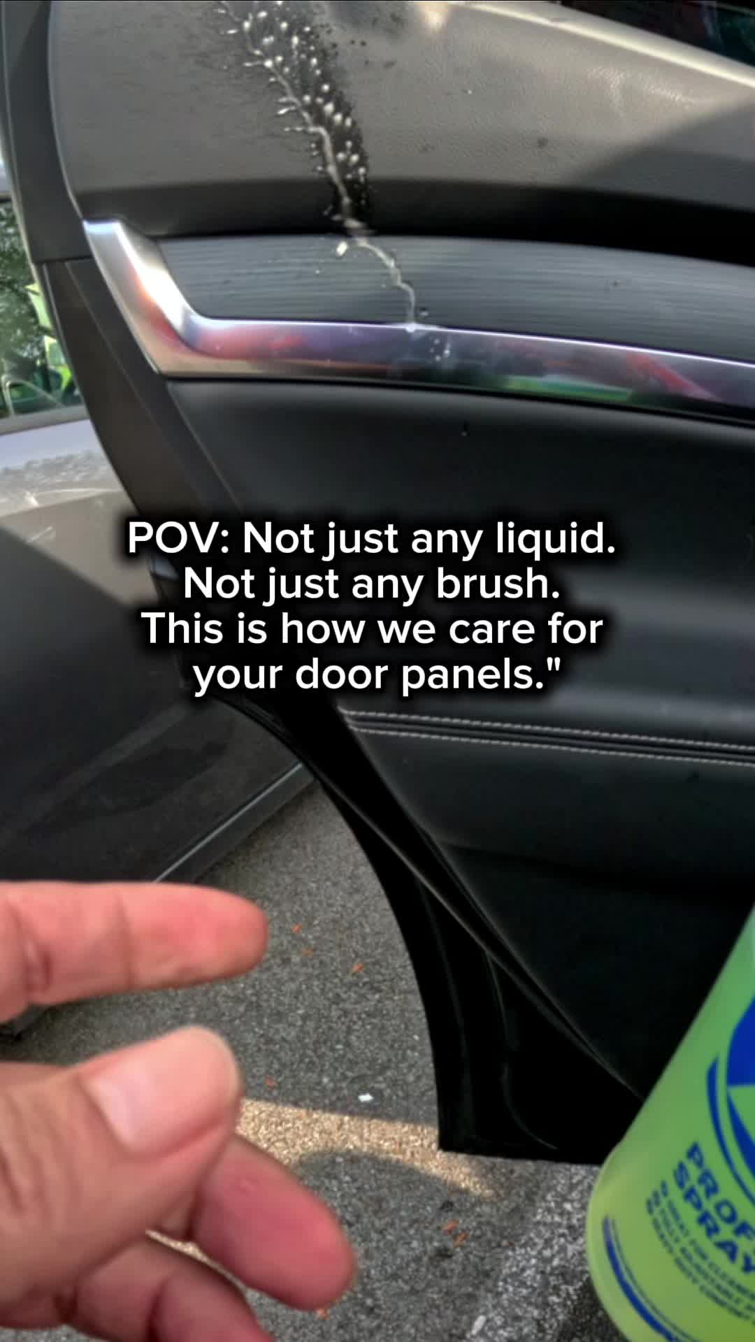 Detailer cleaning a vehicle door panel with a soft brush and interior cleaner